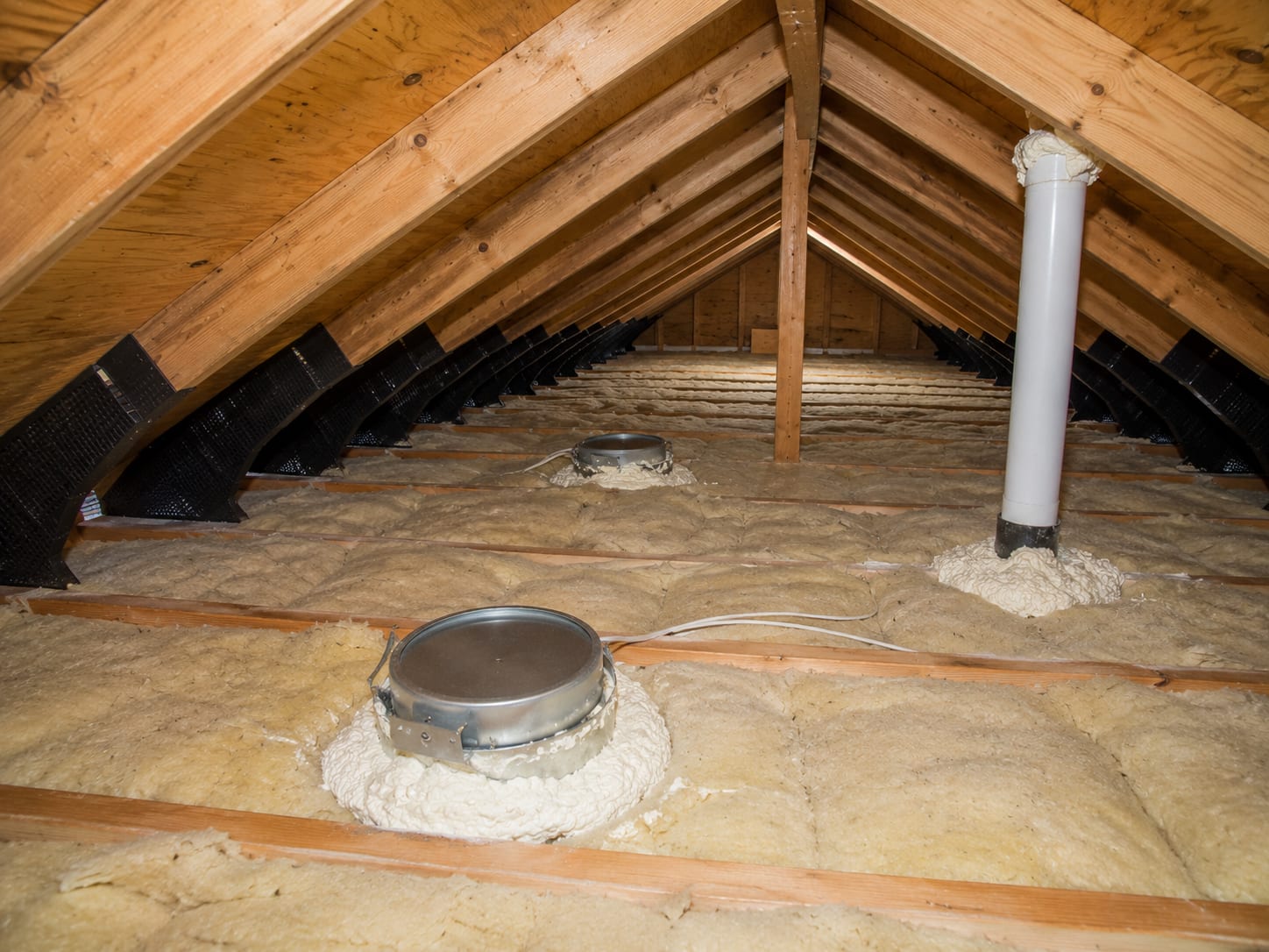 Dry attic with sealed recessed-light and pipe penetrations and clear soffit-to-ridge ventilation baffles