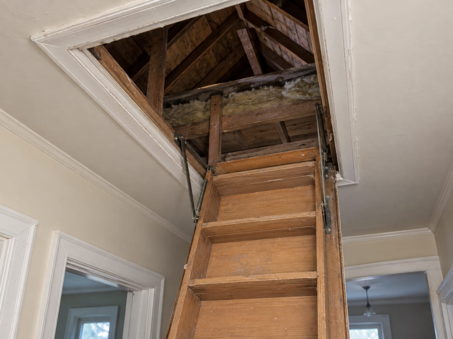 The open ceiling hatch to the attic of an older Trenton, New Jersey house, seen from the upstairs hallway with a folded wooden ladder