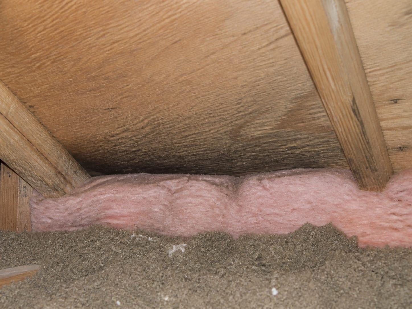 Fibreglass batt insulation pushed hard into the eave closing off the soffit intake where the rafter meets the top plate, in a Warren, New Jersey attic