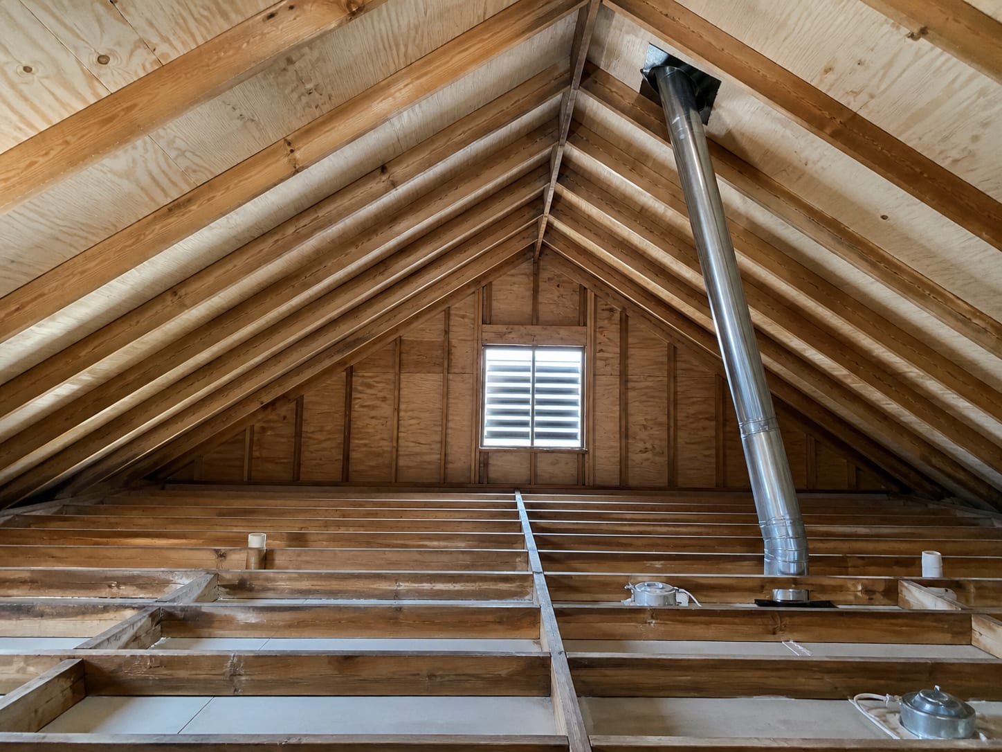 The underside of attic roof sheathing cleaned back to pale timber between rafters with insulation removed and ceiling joists exposed, in Warren, New Jersey