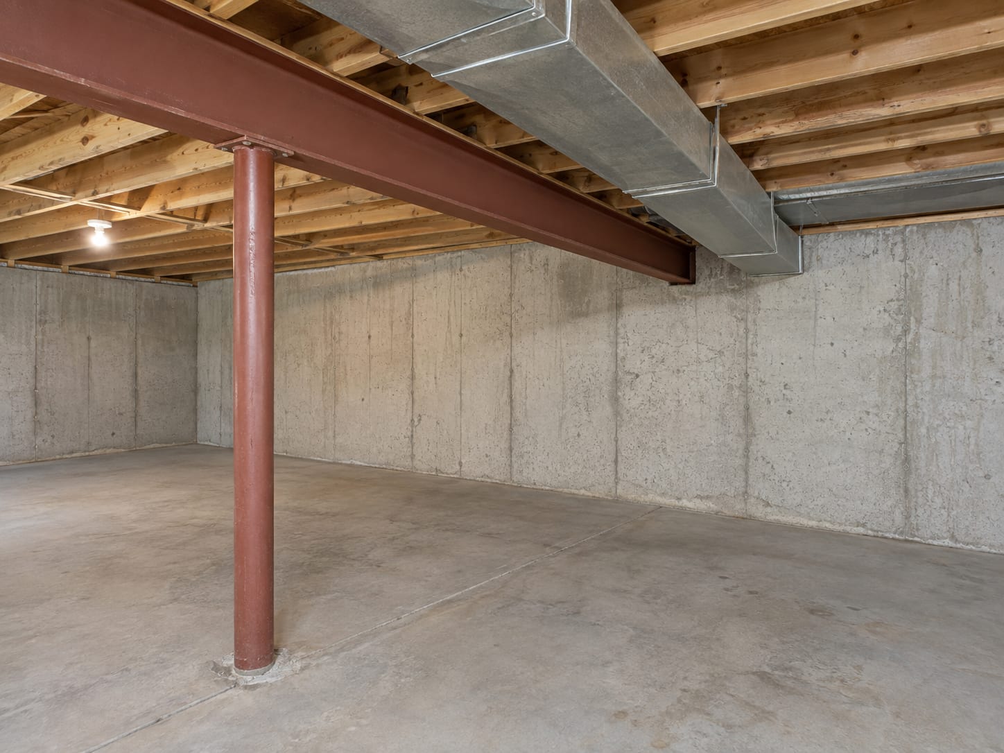 Basement in a Robbinsville, New Jersey house with a steel beam and metal ductwork crossing a low ceiling above a concrete floor