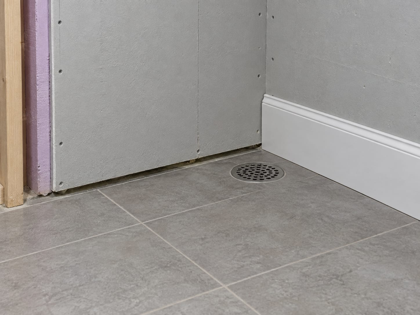 A basement wall in Trenton, New Jersey finished with cement board, a painted surface, vinyl trim, and a porcelain tile floor