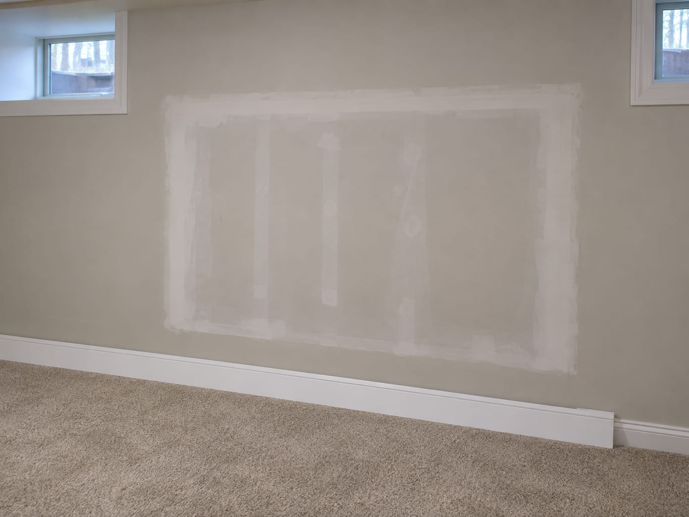 Lower level wall in a Robbinsville, New Jersey house with a fresh section of taped and mudded drywall, unpainted, set into old painted wall