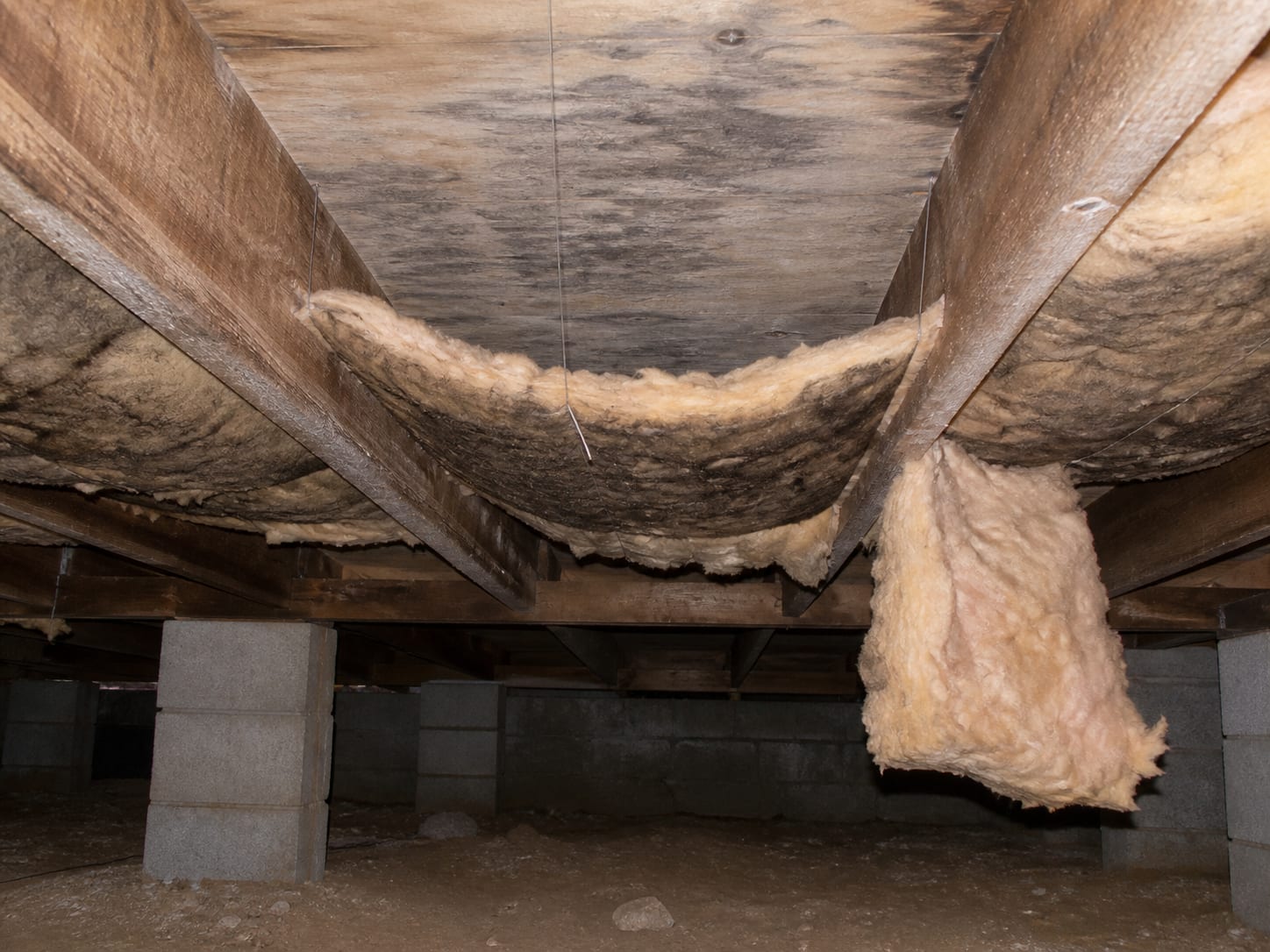 Fibreglass batt insulation between floor joists sagging away from the subfloor and darkened along its lower face, a section hanging loose, in Plainsboro, New Jersey