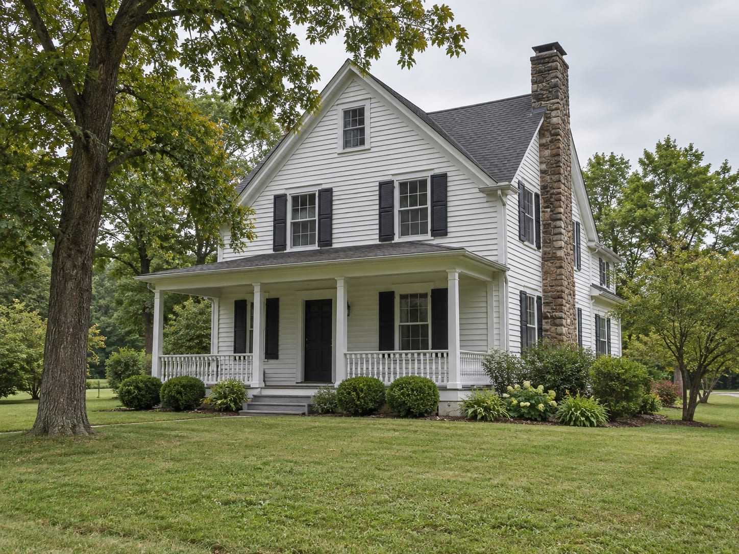 White clapboard farmhouse in Robbinsville, New Jersey with a gabled roof, a front porch with railings and a lawn seen from the street