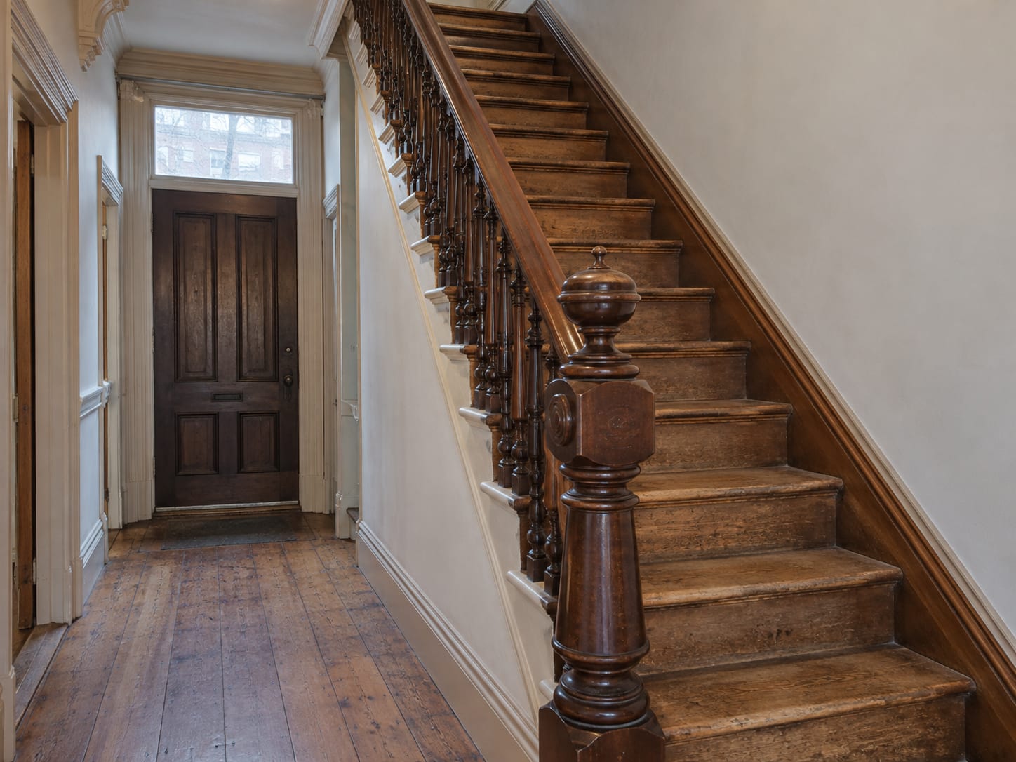 The stair in a Trenton, New Jersey rowhouse hallway with a turned newel post, balusters and softly worn treads