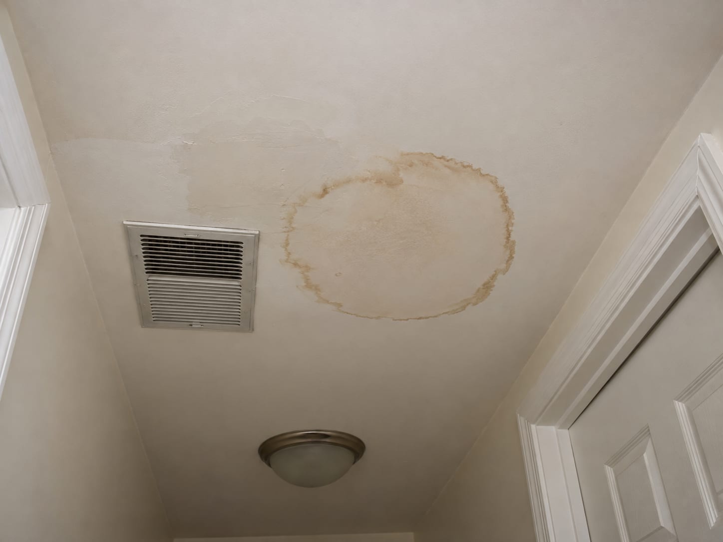 Second floor hallway ceiling in a Bridgewater, New Jersey home with a brown ring stain and a painted over patch beside an air supply vent