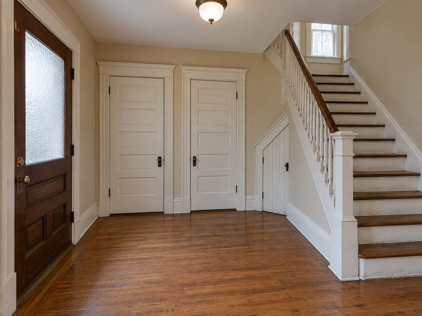 Interior entry hall of a two-family house in Trenton, New Jersey with two closed apartment doors, a staircase and a cellar door