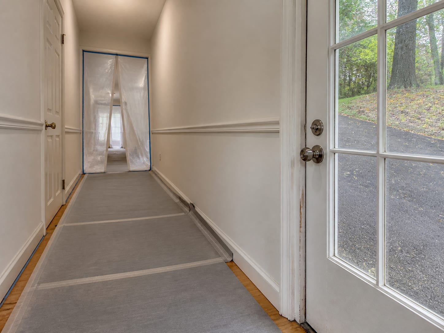 Adhesive backed floor protection running from a containment doorway along a hallway and out through a side entry, in a Warren, New Jersey home
