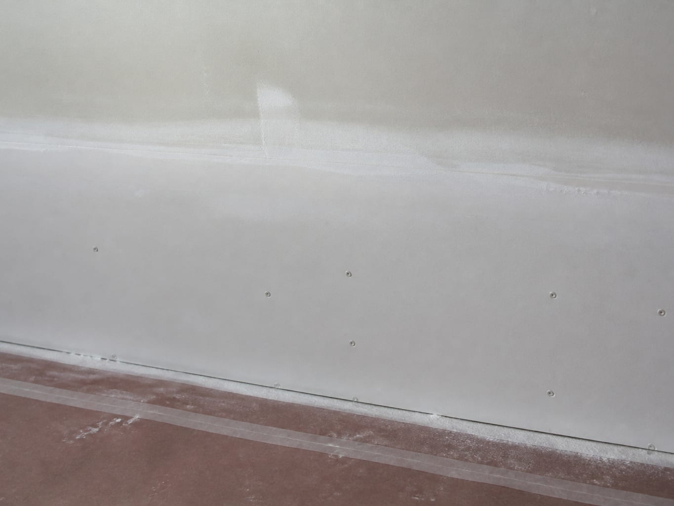 A close view of the taped and floated seam where new drywall meets the original wall above the line where removal stopped in a Livingston rebuild