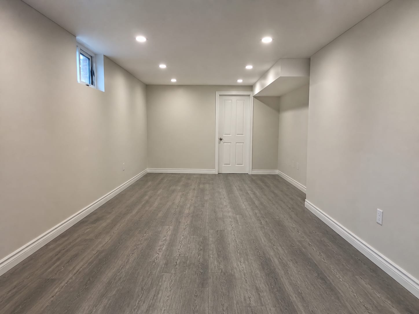 A plainly finished lower level with fresh painted drywall, new baseboard and plank flooring, empty and complete, in Warren, New Jersey