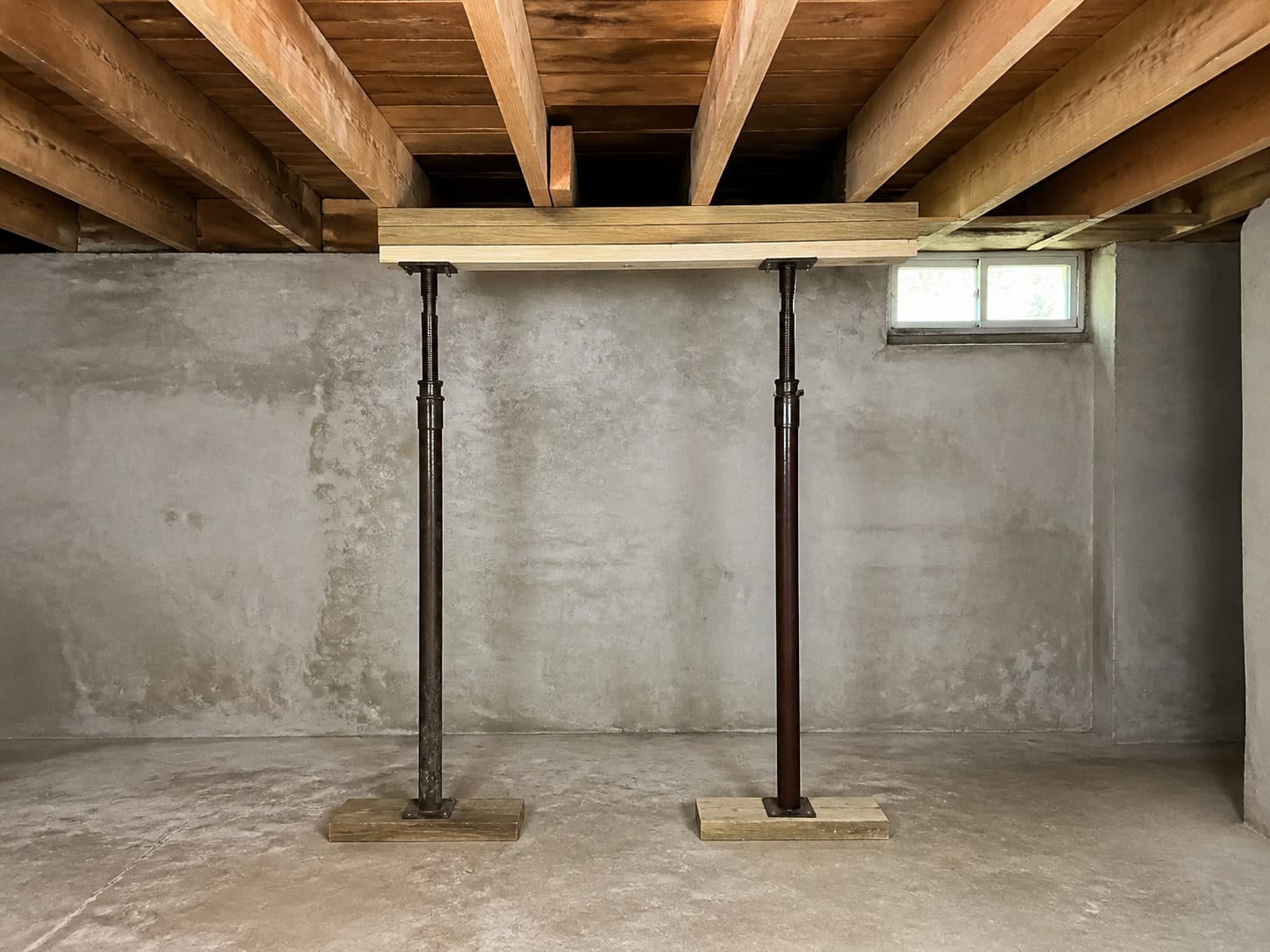 Adjustable steel props standing on timber sole plates supporting a built up beam while a joist repair is carried out, in a Warren, New Jersey basement