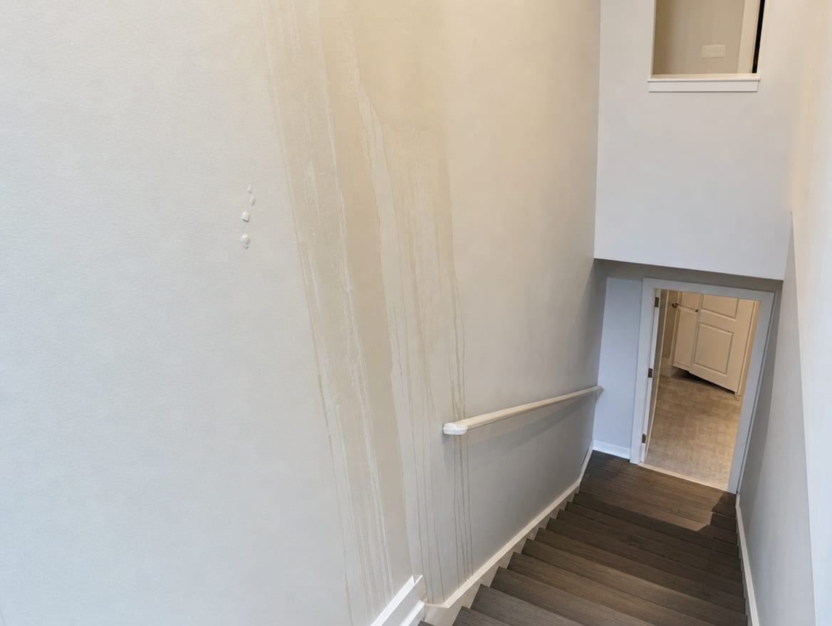 Water staining tracking down a modern townhouse stairwell wall showing water crossing between floors