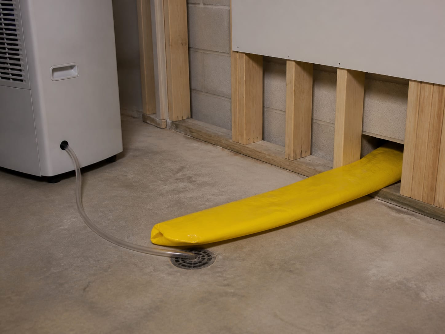 Yellow lay flat ducting running from a dehumidifier along the base of an opened wall toward a cavity being dried, in Warren, New Jersey