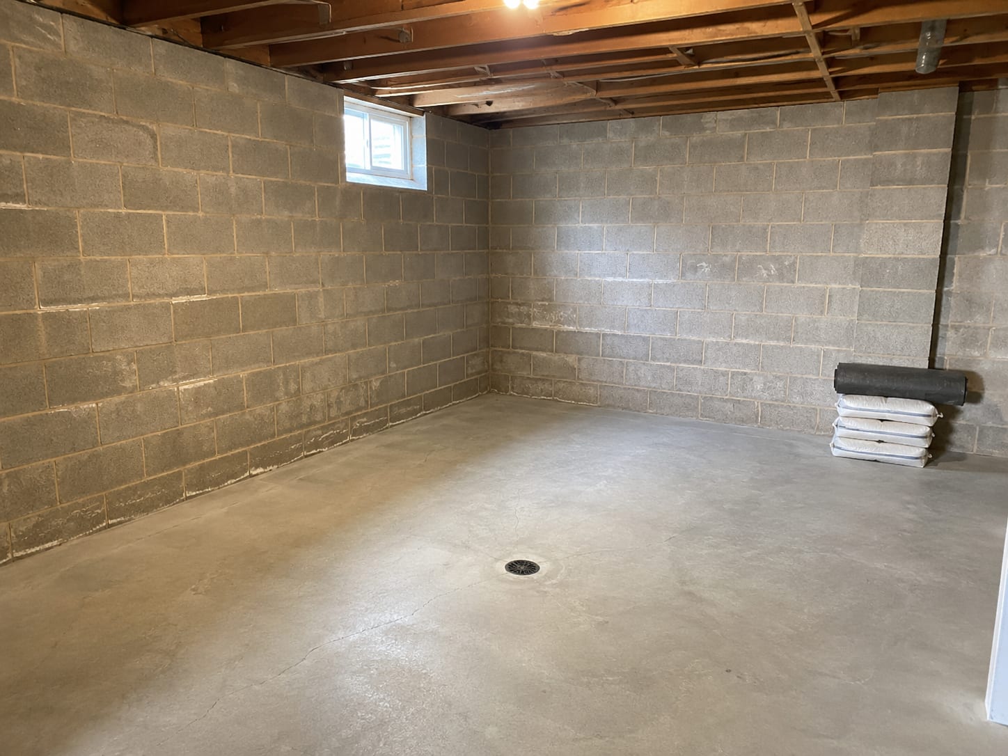 Clean dry unfinished basement interior after completed drying process showing light-toned concrete block walls and dry concrete floor ready for restoration