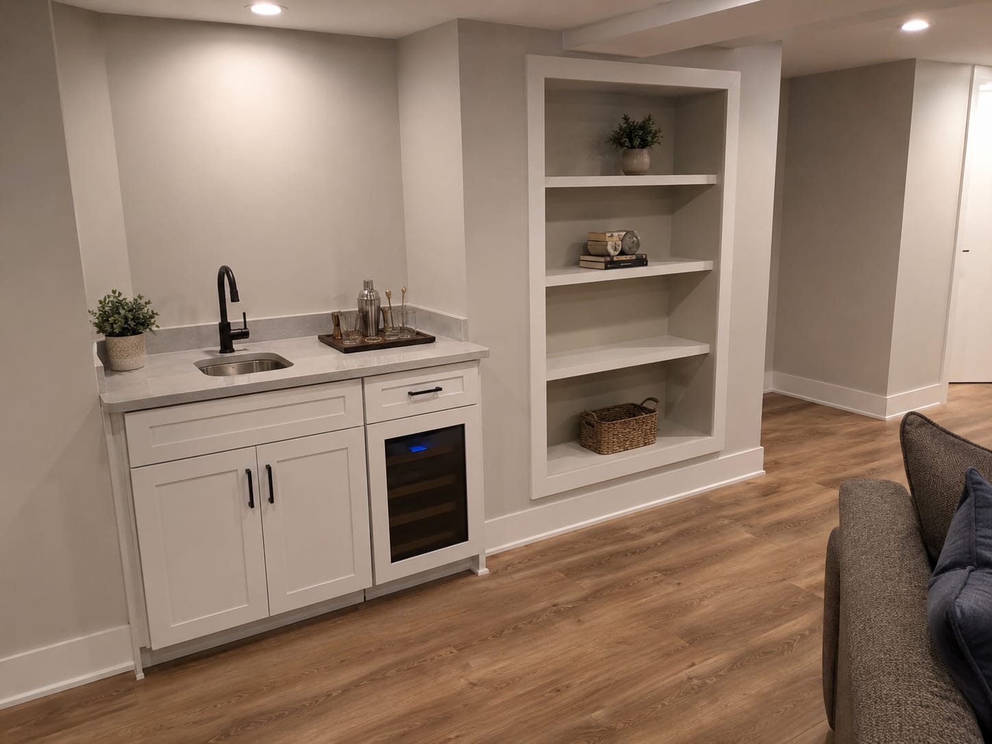 Finished basement corner with a small custom built-in bar counter, painted cabinetry, and recessed shelving set into a framed wall in a New Jersey home