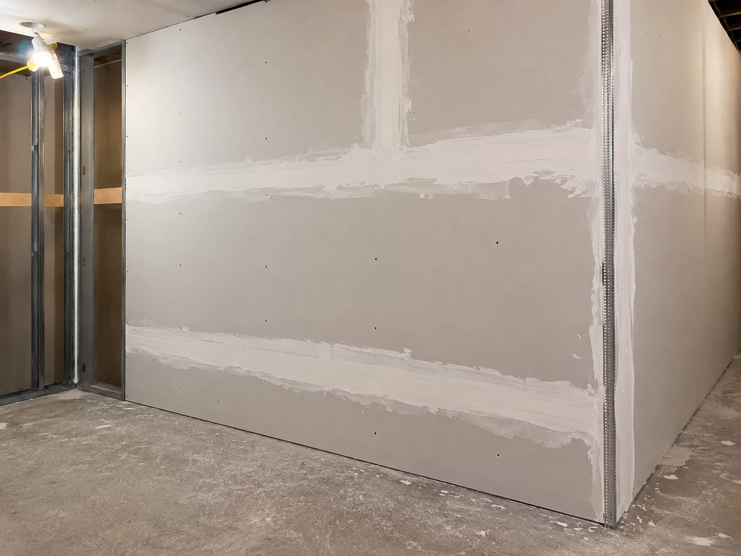Newly framed and drywalled basement walls with taped seams and metal corner bead ready for primer in a New Jersey home