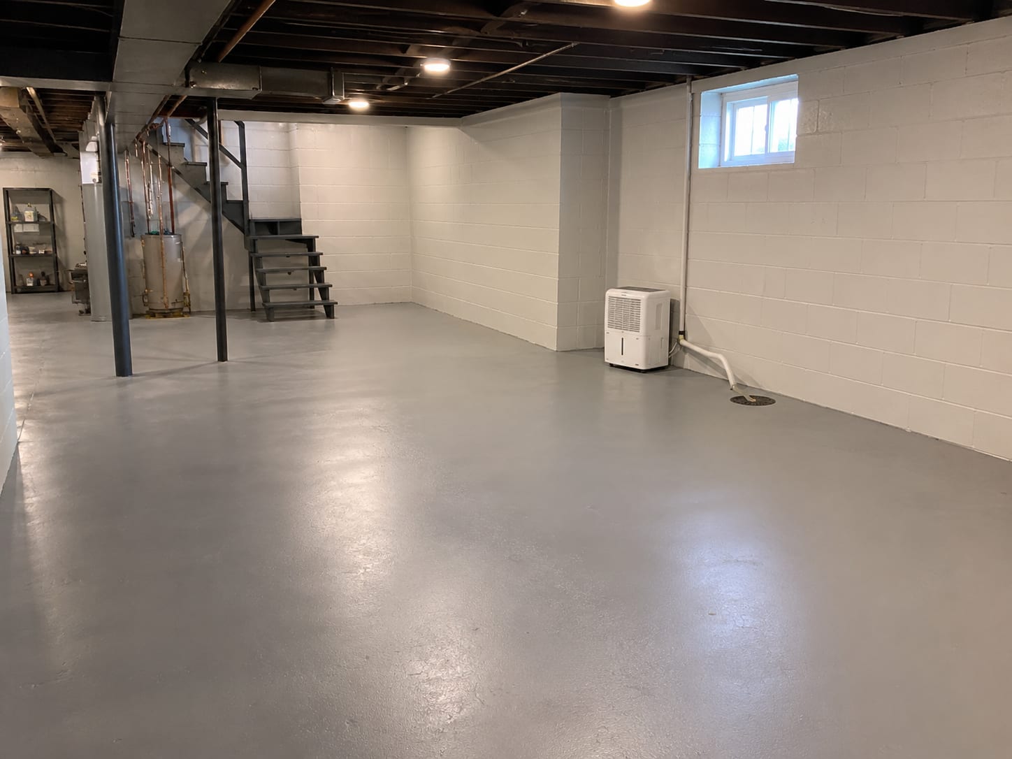 A clean, dry finished basement in a New Jersey home with sealed concrete floor and a dehumidifier running quietly against the wall, conveying a protected, completed result