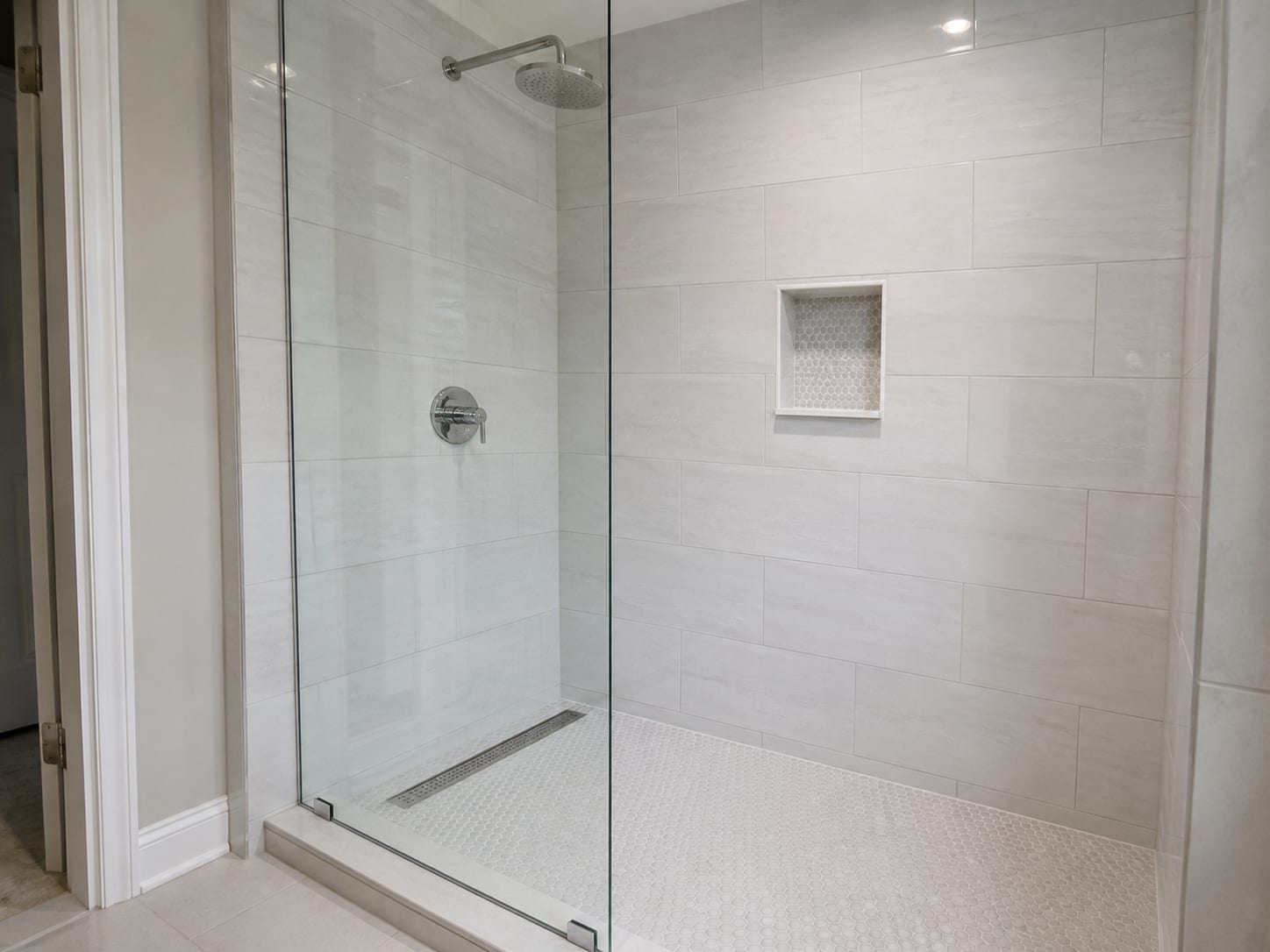 Newly tiled walk-in shower enclosure with clean grout lines, chrome linear drain, and glass panel door inside a renovated New Jersey bathroom