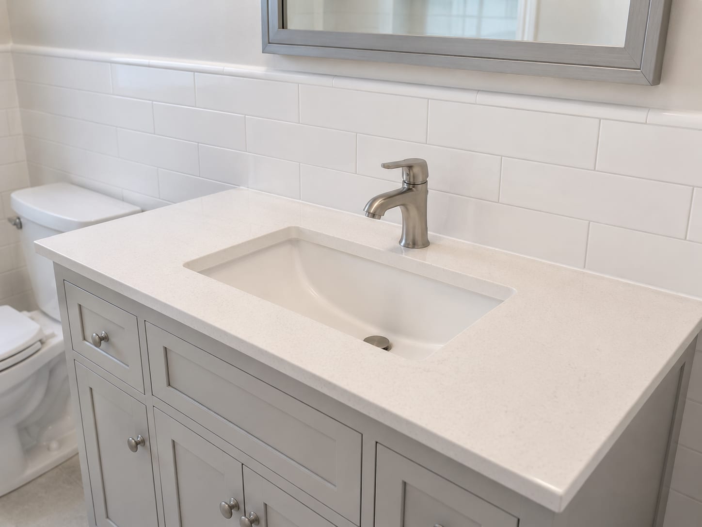 Newly installed bathroom vanity cabinet with undermount ceramic sink, brushed nickel faucet, and quartz countertop in a renovated New Jersey bathroom