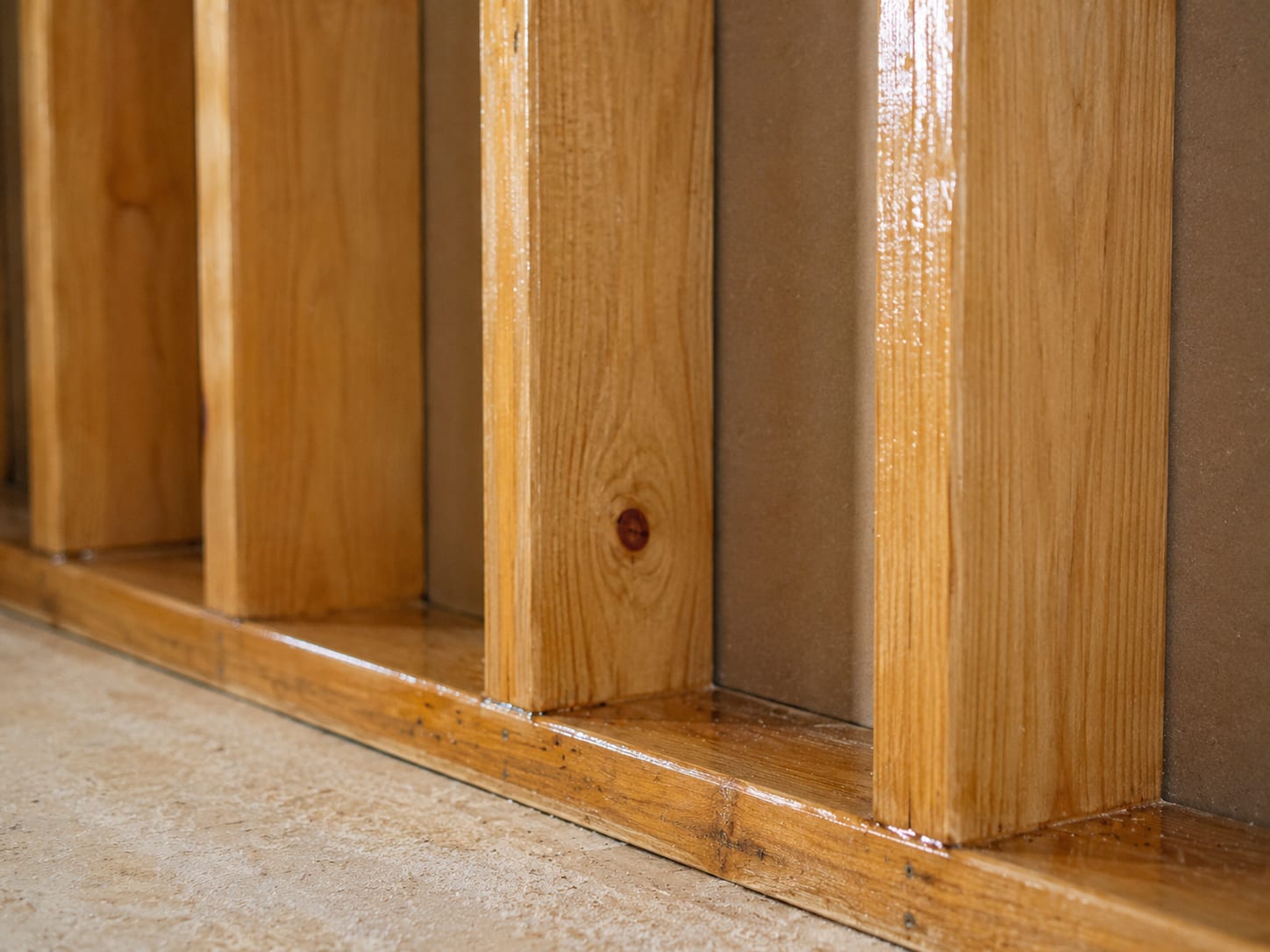 A close-up of clean, treated wood wall framing with a clear protective encapsulant coating in a New Jersey home, showing thorough completed remediation