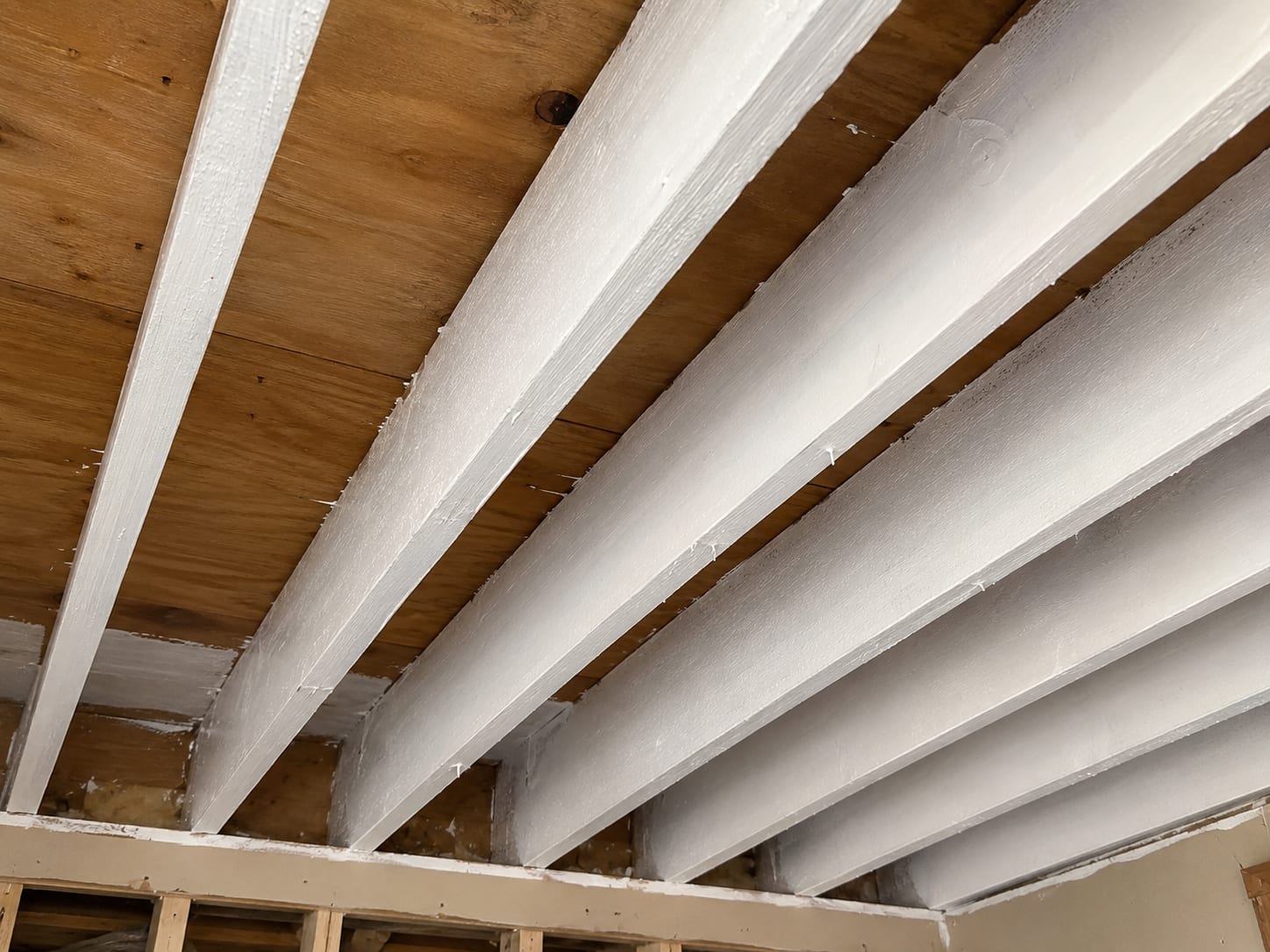 Exposed ceiling joists coated with white antifungal encapsulant in a remediated New Jersey residential attic framing cavity