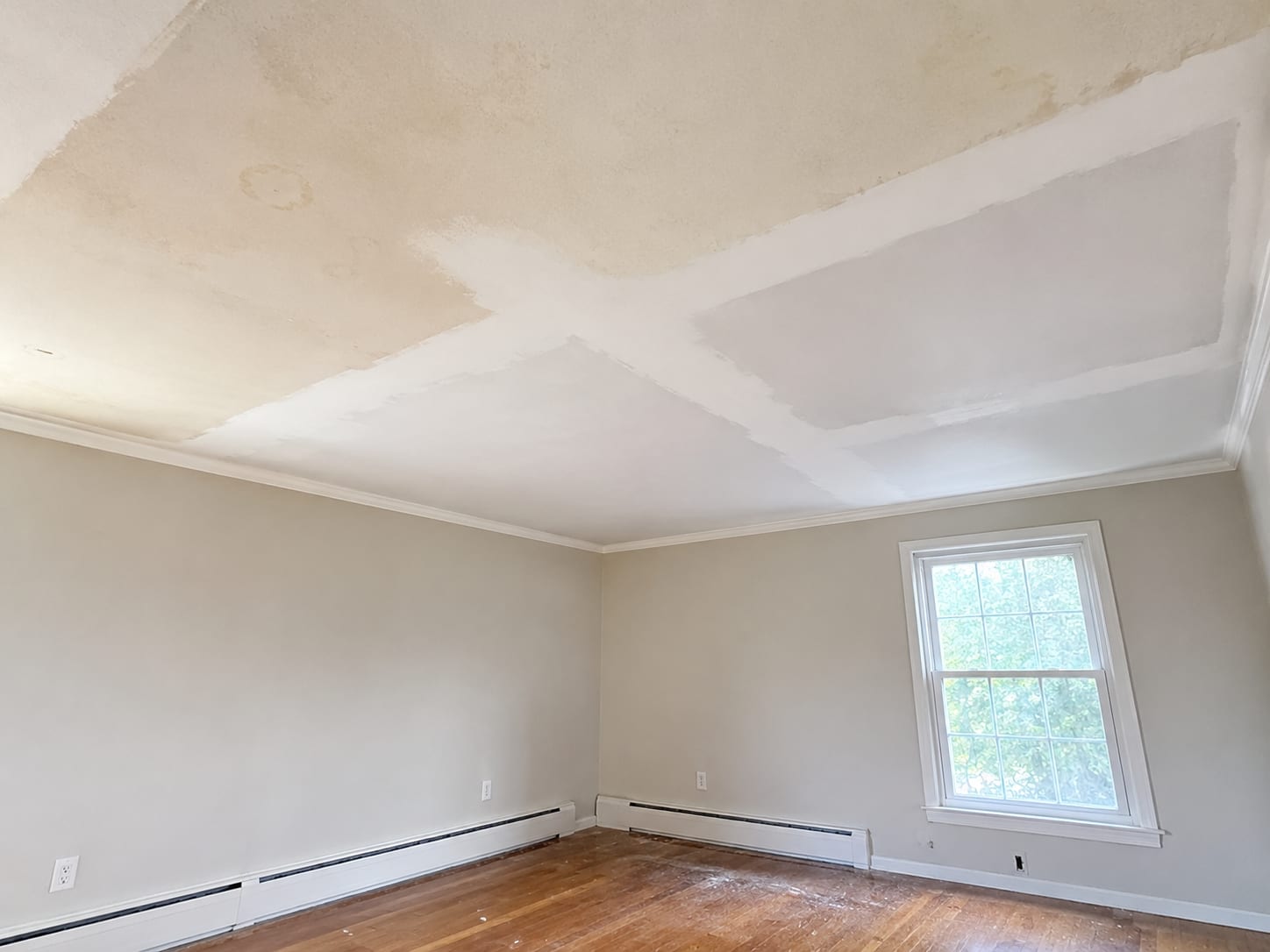 Remediated residential ceiling with freshly sealed and primed drywall patches in a colonial-style New Jersey home interior