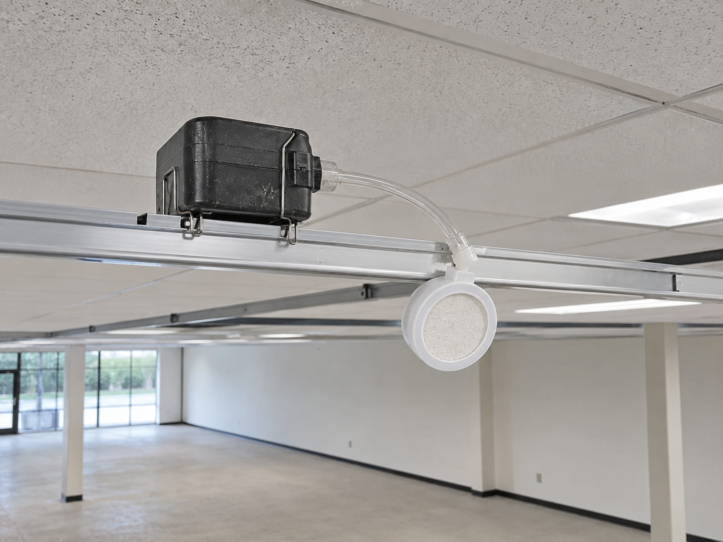 Air quality sampling pump with cassette attached sitting on a commercial drop ceiling grid rail in a cleared remediation zone ready for post clearance testing