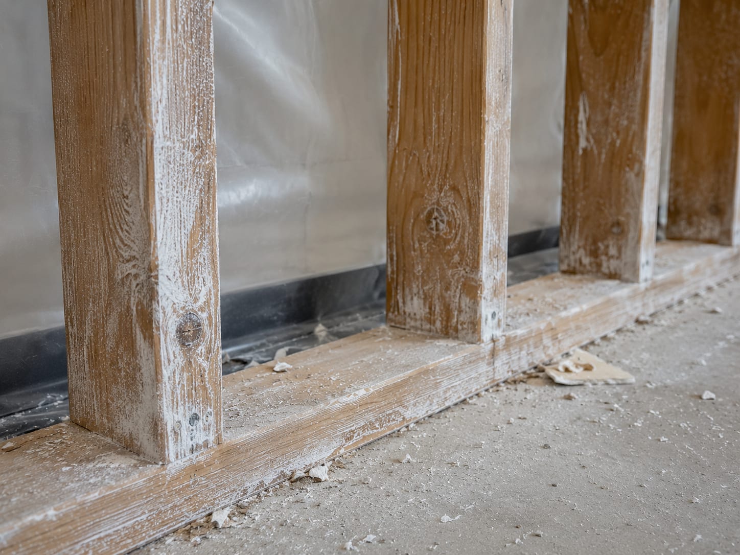 Close-up of exposed commercial building wall framing after mold removal showing treated wood studs with dried antimicrobial coating and cleaned surfaces