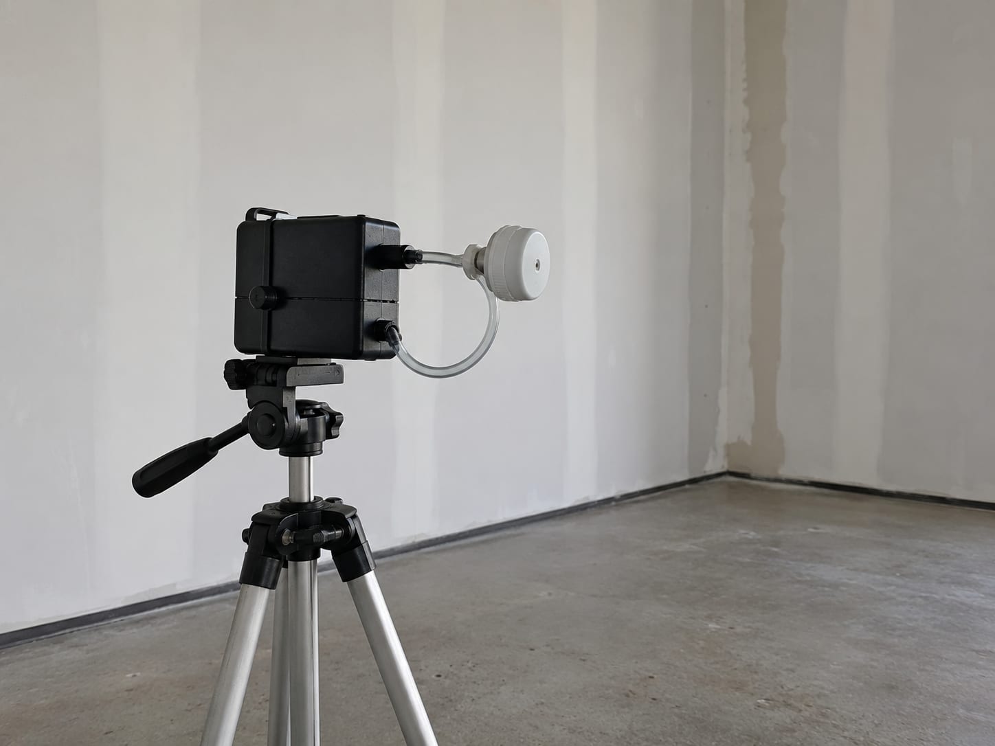 Close view of an air sampling pump and cassette mounted on a tripod inside a commercial retail space during post-remediation indoor air quality testing