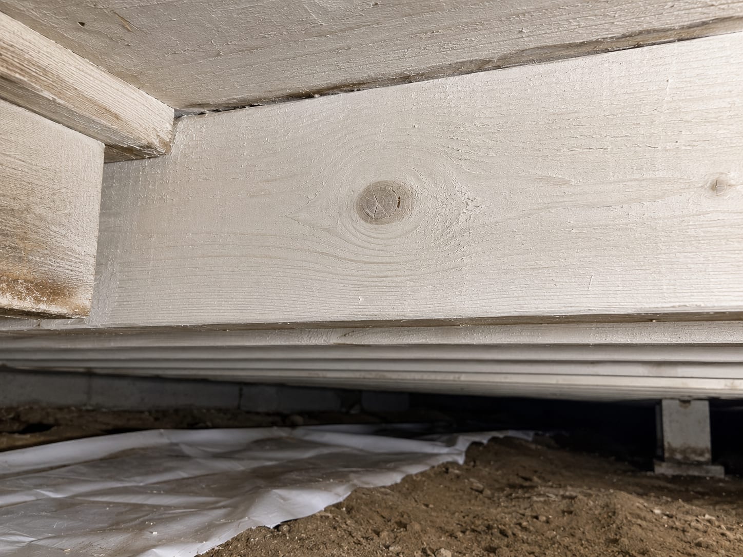 Close-up of a treated wooden floor joist in a New Jersey crawl space showing clean light-colored wood surface after mold remediation with antifungal coating applied