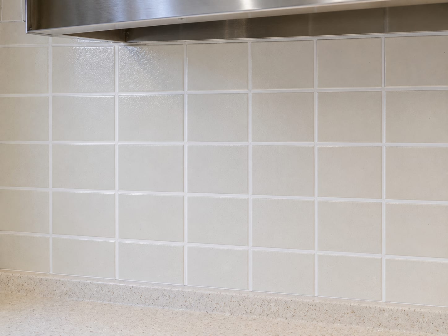 Close-up of freshly scrubbed kitchen tile backsplash and grout lines in a mid-century New Jersey home showing bright white grout and clean ceramic tile surface after deep cleaning