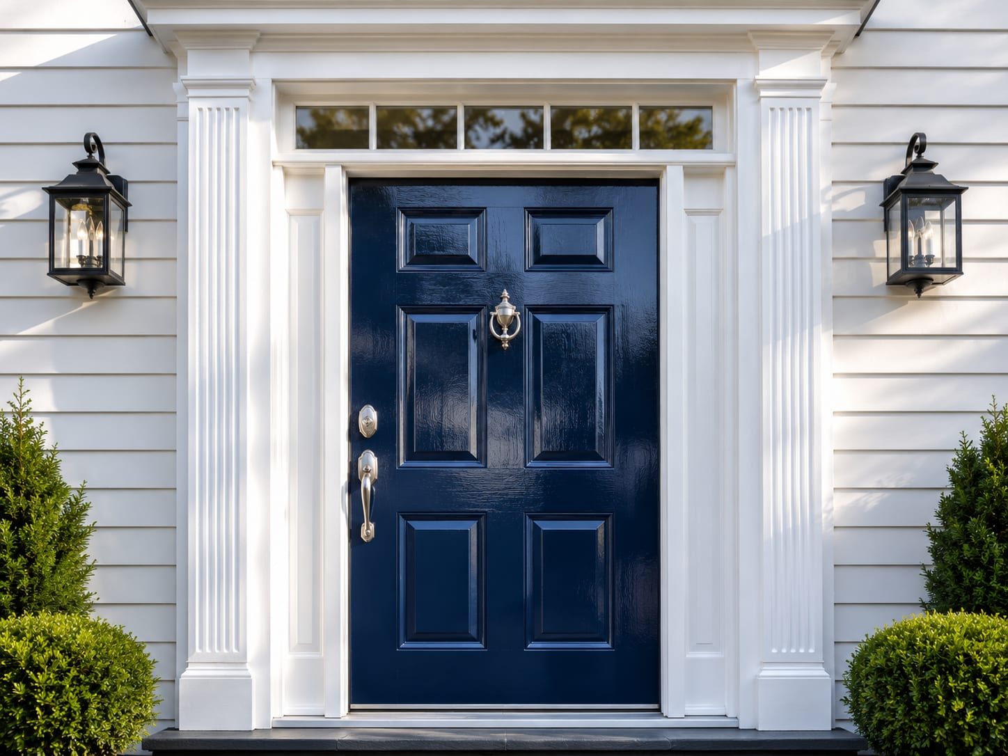 Freshly painted deep navy blue front door with white pilaster trim and transom window on a colonial home in New Jersey