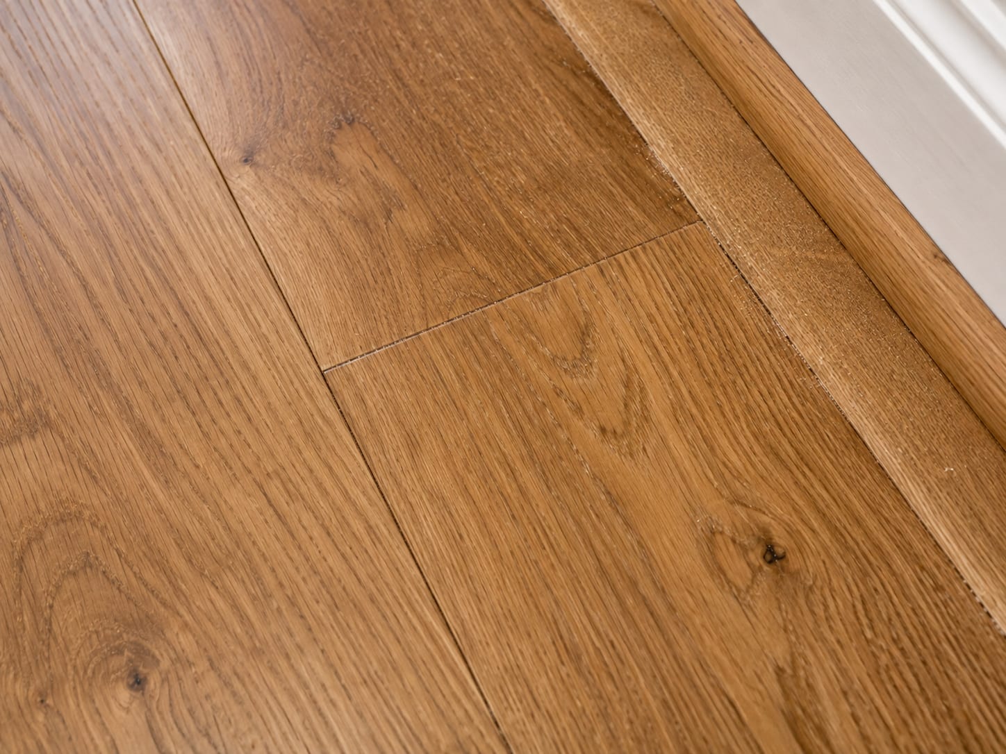 Close-up of freshly installed hardwood plank seams showing tight tongue-and-groove joints and natural oak grain texture in a New Jersey home