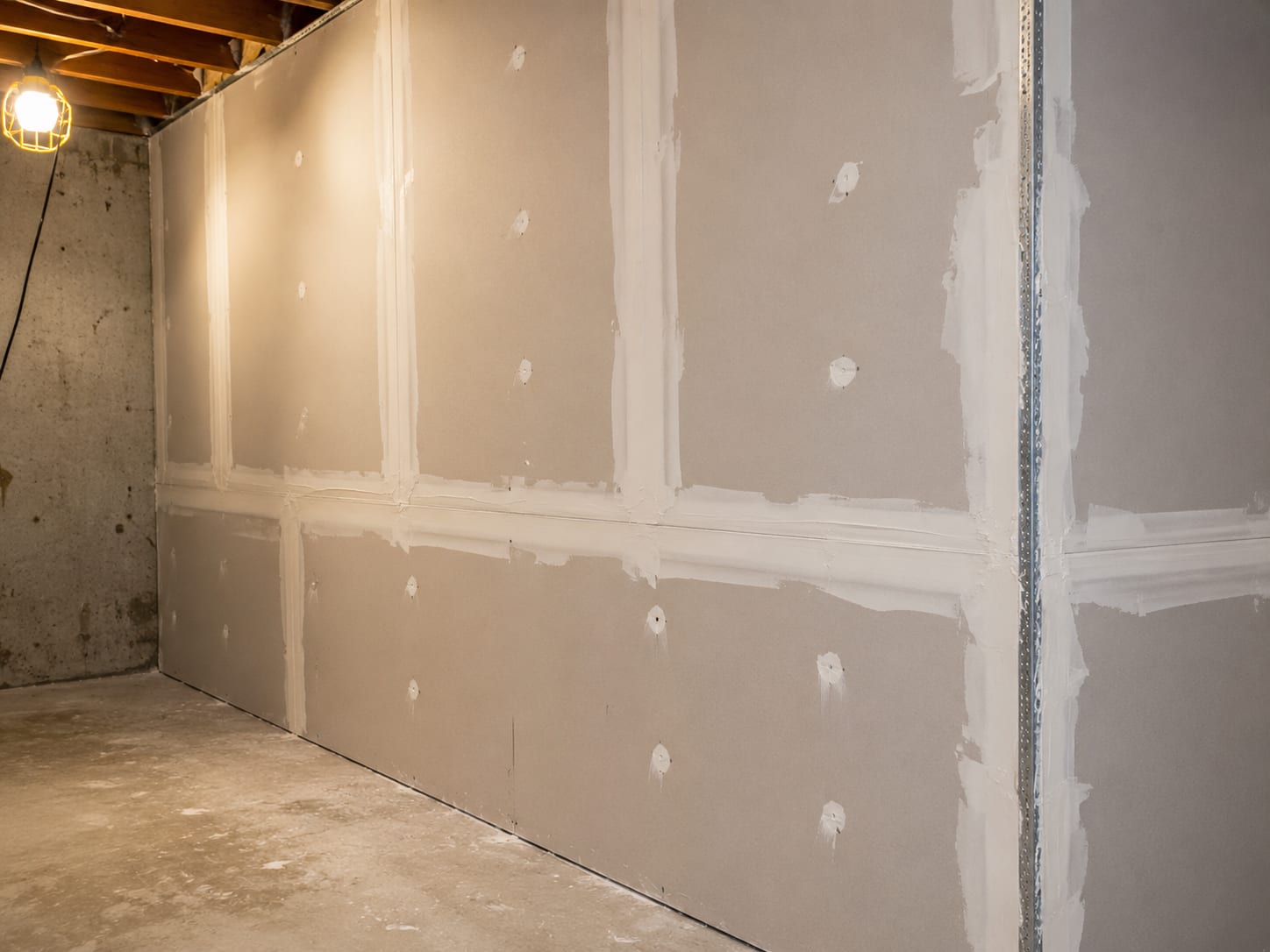New drywall sheets installed and taped in a residential basement room during post-remediation general contracting build-back
