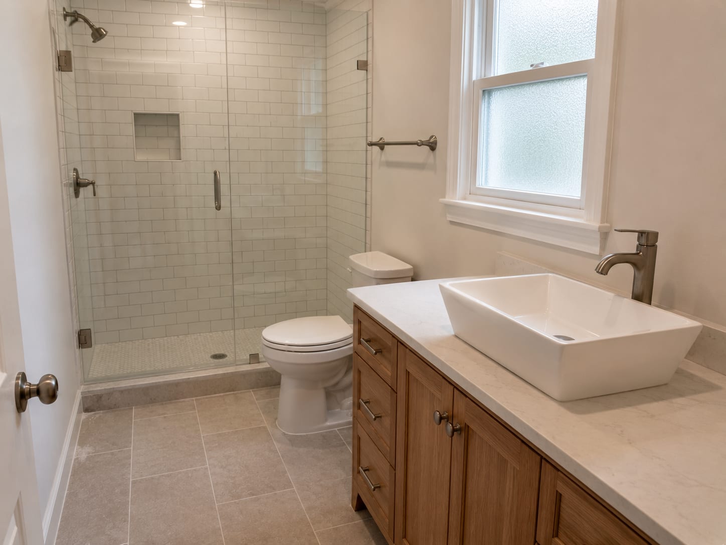 Freshly tiled full bathroom in a New Jersey home showing a new porcelain floor, subway tile shower surround, and a freestanding vanity with a vessel sink under a single frosted window