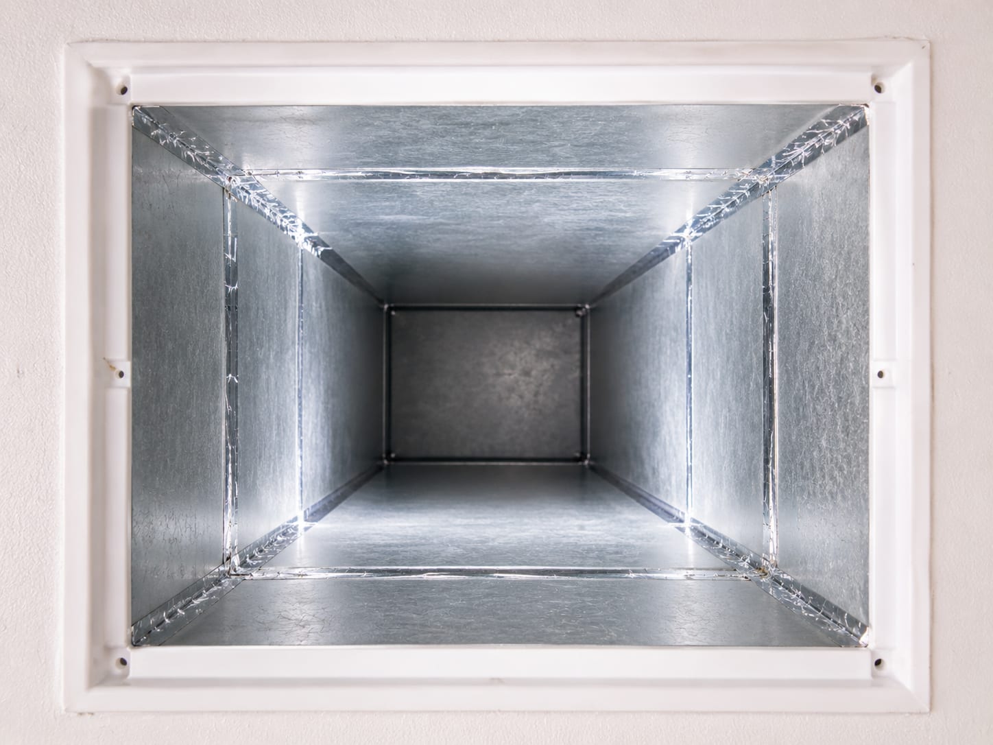Bright clean interior of a rectangular sheet-metal HVAC duct after remediation showing smooth bare metal walls with no visible mold or debris