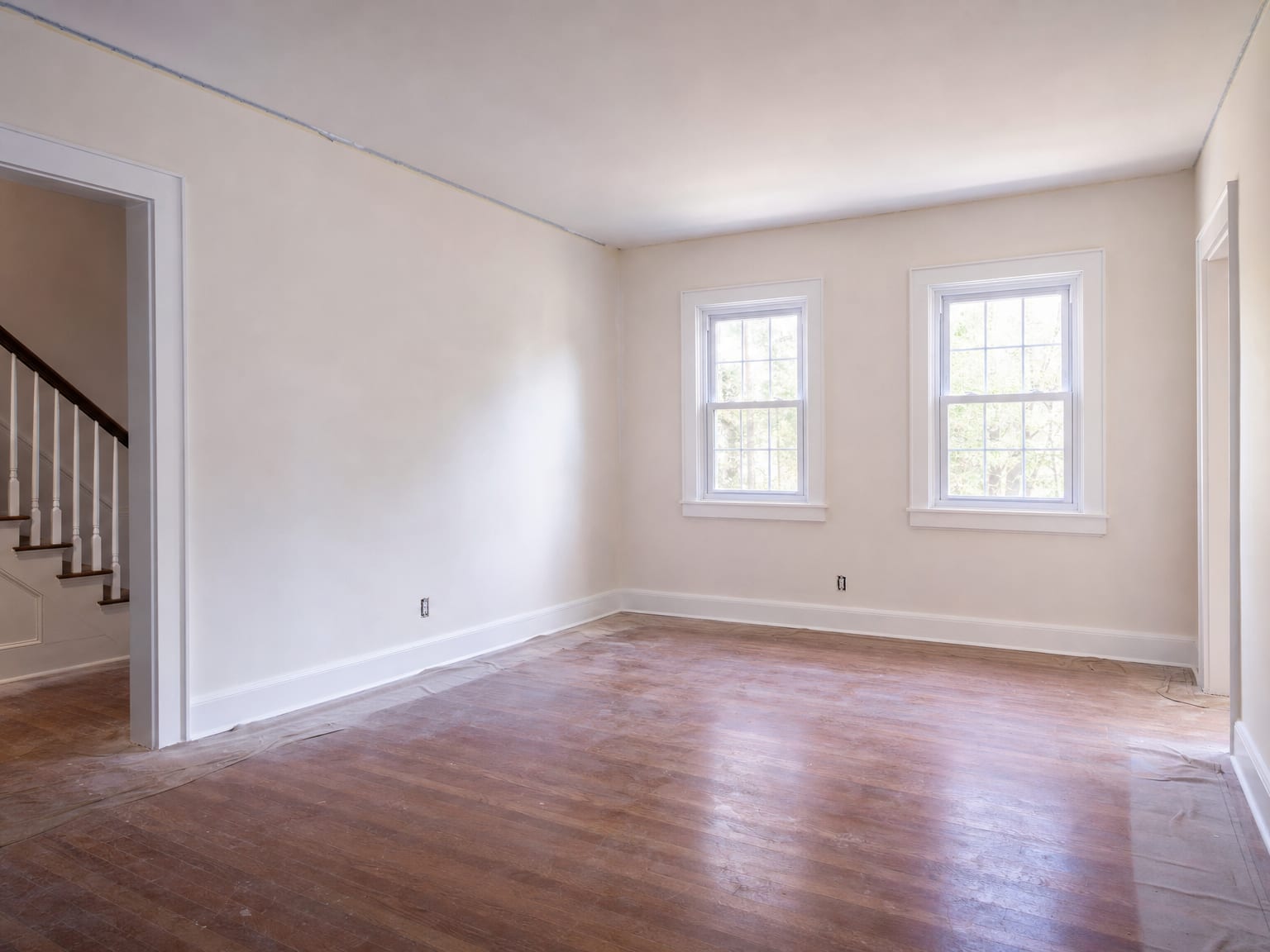 Freshly painted living room with smooth warm white walls, natural light from double-hung windows, and clean trim in a colonial-style New Jersey home