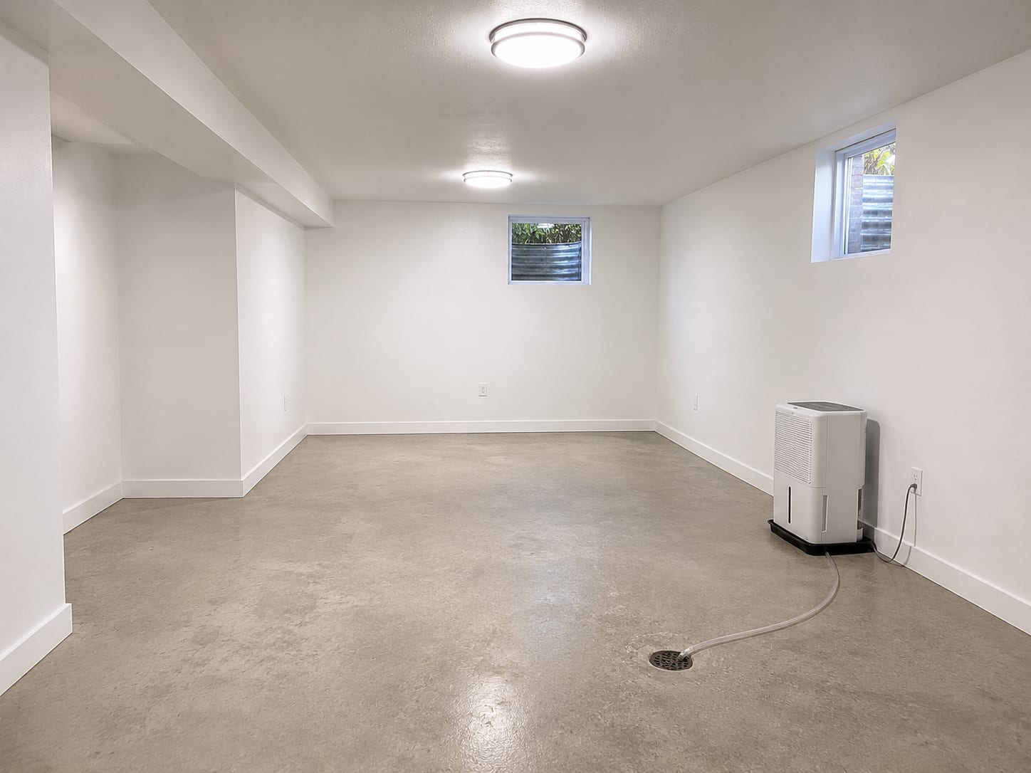 Freshly painted clean basement interior with new drywall and bright lighting after mold remediation
