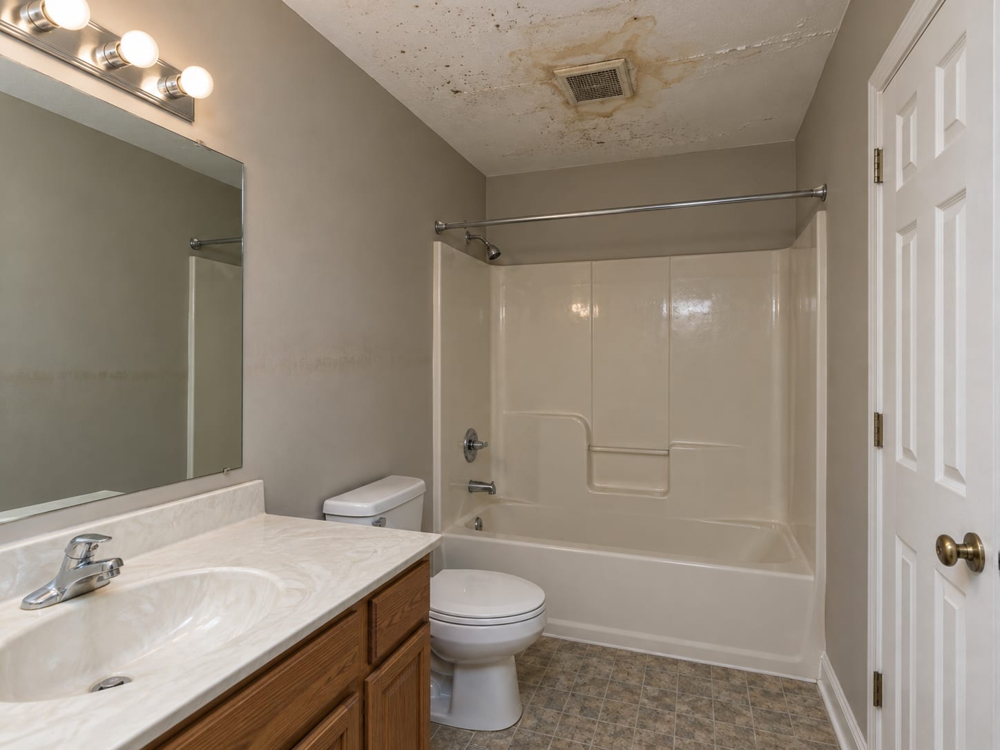 A stained, spotted ceiling around the bathroom fan grille in a Dayton townhouse points to steady humidity above the tub.
