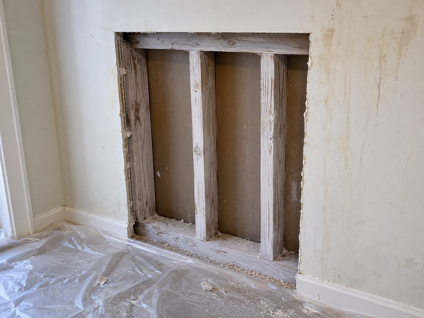 Partially removed drywall in a residential room exposing mold-treated wall cavity and framing after professional remediation in New Jersey