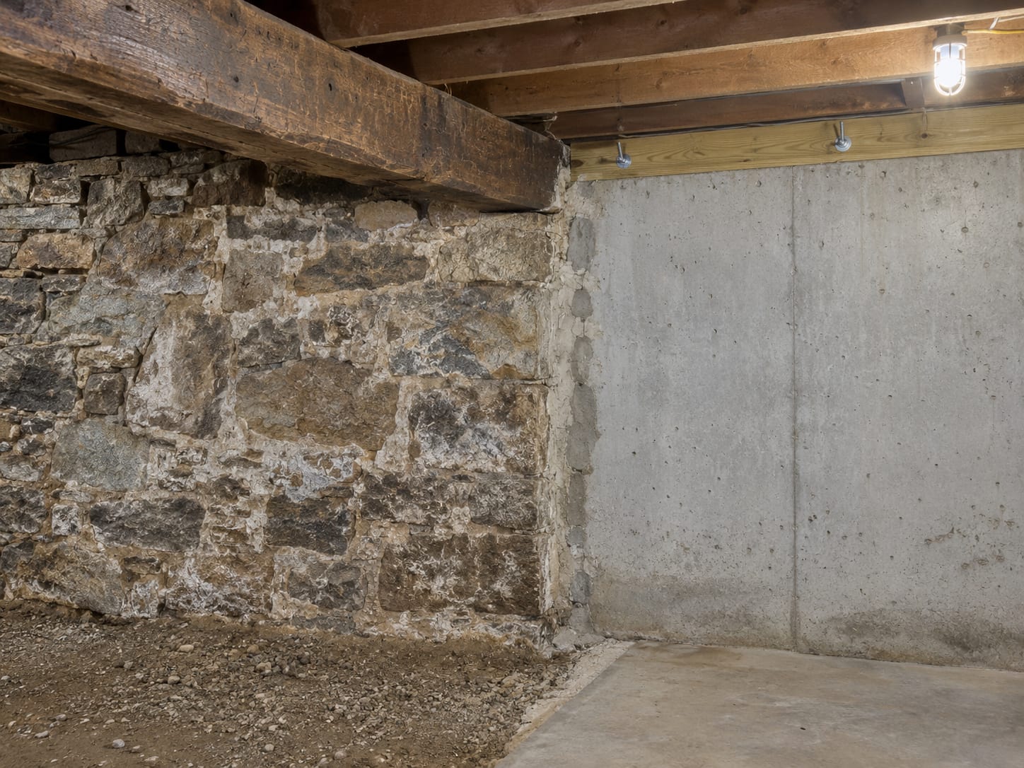 A cellar where an old fieldstone foundation wall with lime mortar and a axe hewn beam meets a newer poured concrete wall with a sill plate, in Harlingen, New Jersey