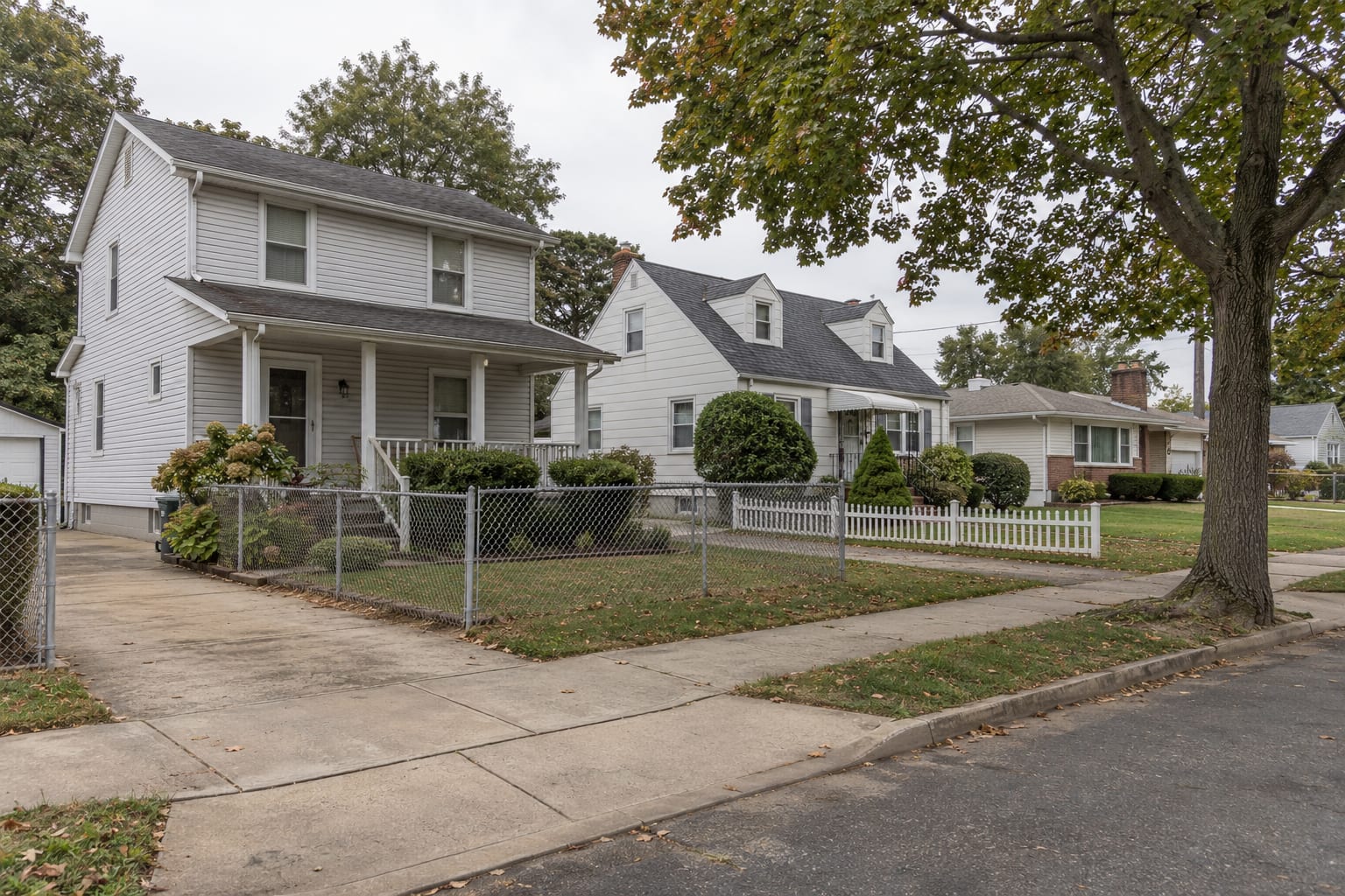 Early twentieth century two storey frame houses with front porches beside Cape Cods and ranches in vinyl siding on small lots with narrow driveways, in Jamesburg, New Jersey