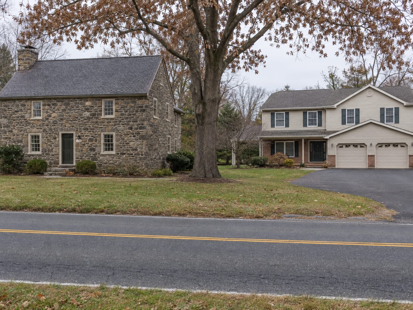 An eighteenth century fieldstone house standing beside a newer two storey vinyl sided colonial with an attached garage on a roadside lot in Kingston, New Jersey