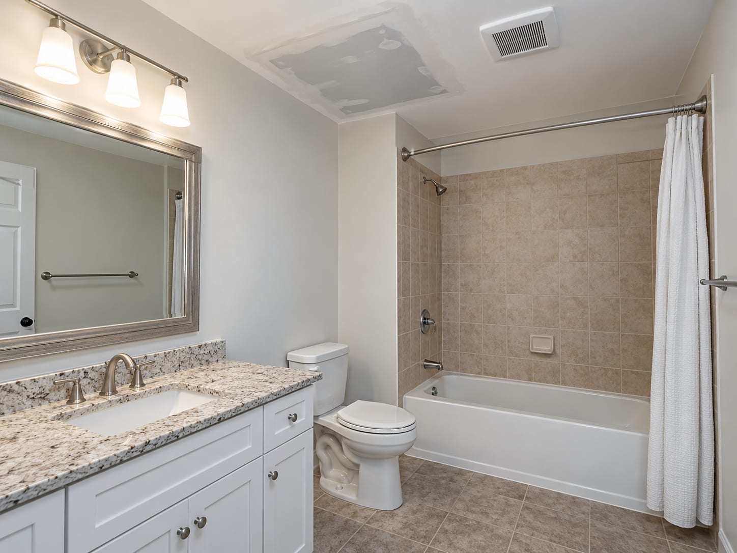 A bathroom ceiling with a squared primed drywall patch beside a new white exhaust fan housing, with the old stain sealed, in a Monroe Township, New Jersey home