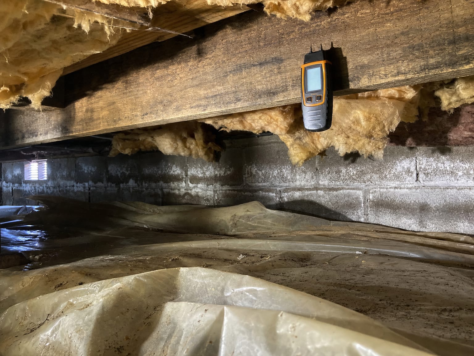 Air sampling pump and cassette mounted on tripod stand inside a finished New Jersey basement with visible moisture staining on lower drywall