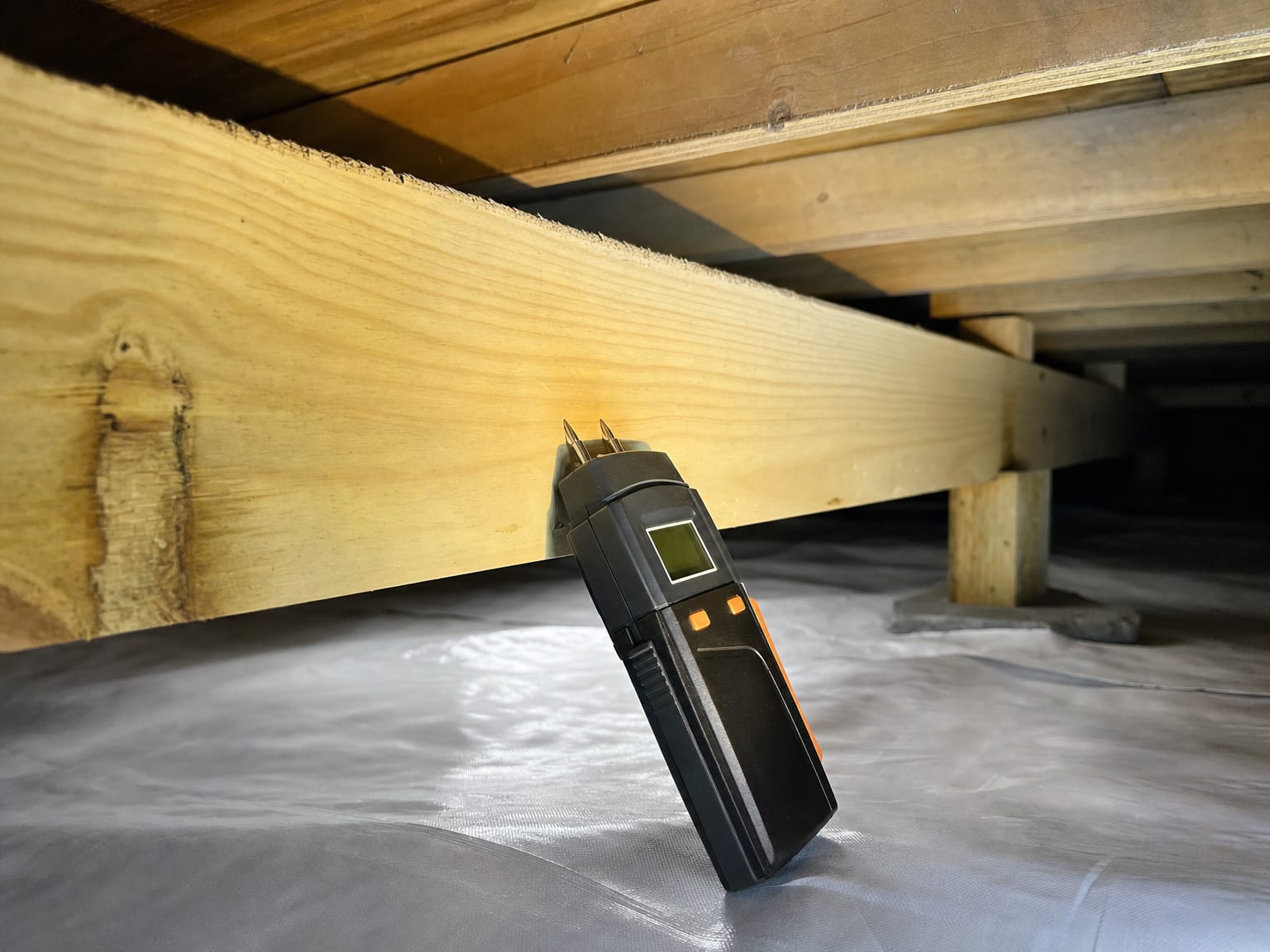 Thermal imaging camera aimed at a clean interior wall showing uniform temperature pattern on a small display