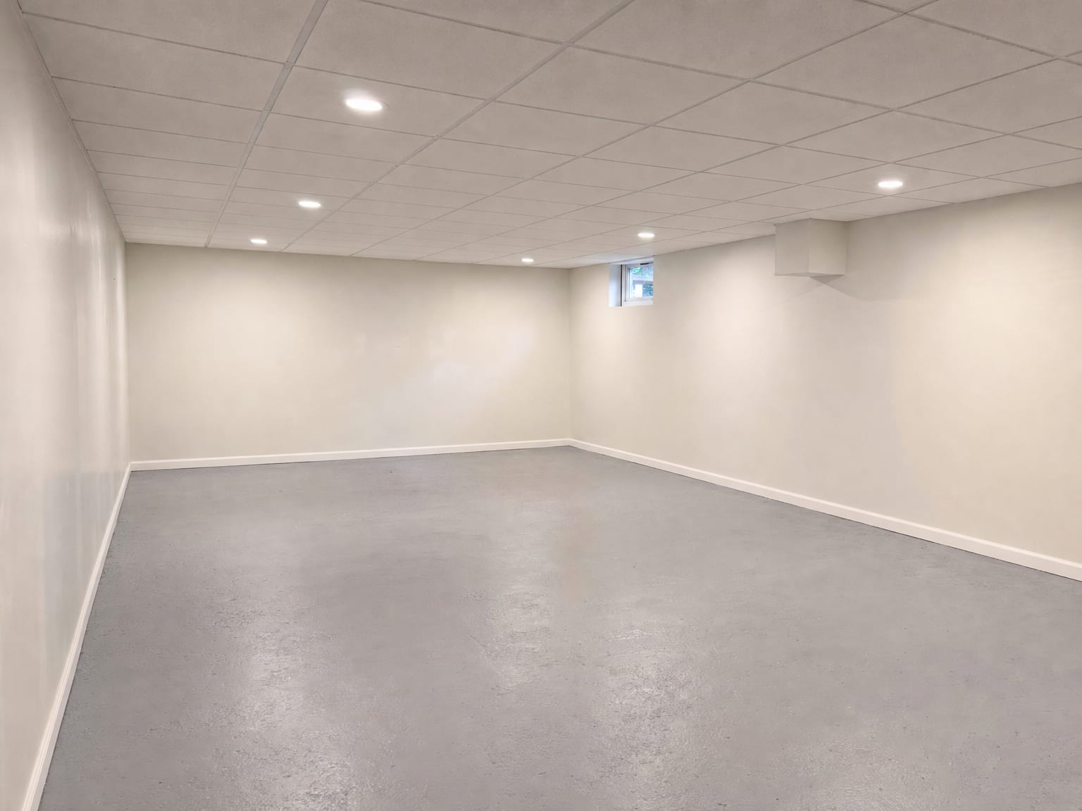 Freshly finished basement interior with new drywall installed, painted walls, and clean concrete floor after completed mold remediation