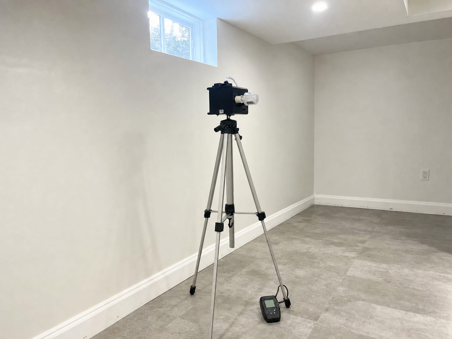 Water-damaged residential living room with axial air movers positioned along baseboard, large refrigerant dehumidifier operating, buckled hardwood flooring drying in progress